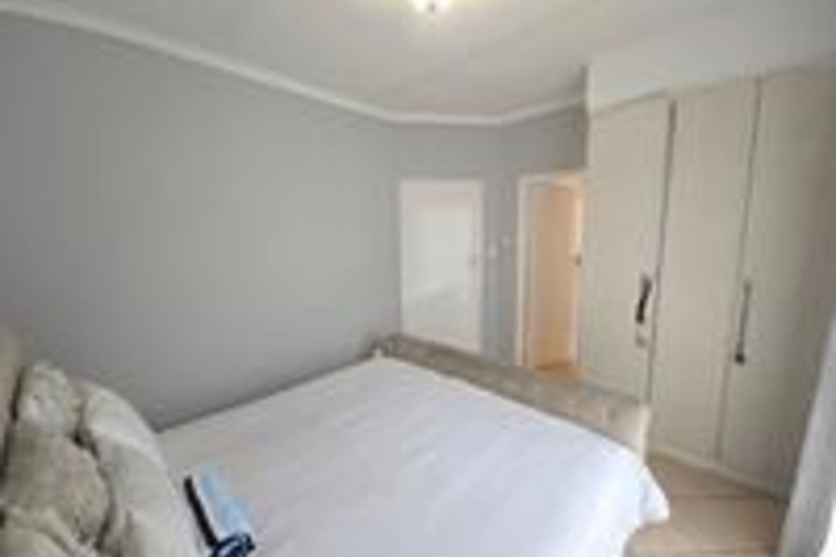 A bedroom featuring built-in cupboards and tiled flooring, providing a functional and neutral living space.
