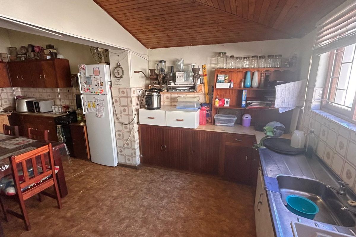 A dated kitchen featuring wood-finish cabinetry, tiled splashbacks, and a timber-paneled ceiling, offering a functional layout with potential for modernization.