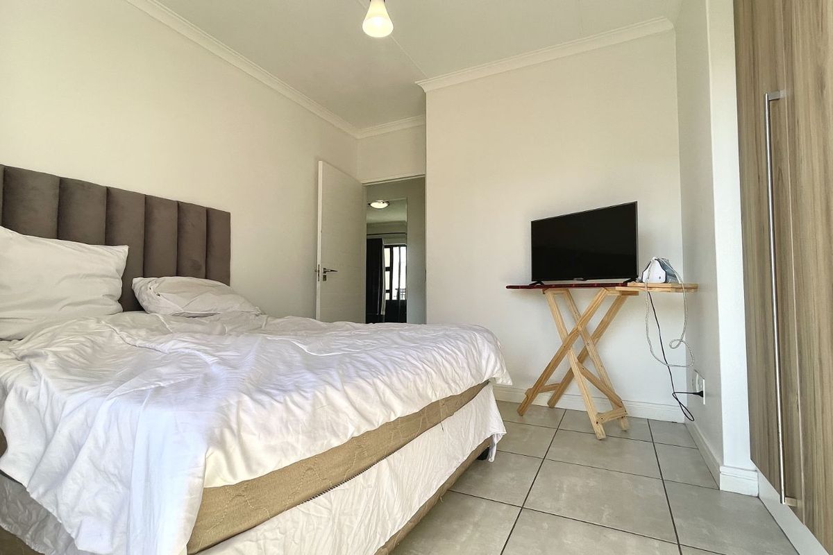 A bedroom featuring tiled flooring, built-in cupboards, and a neutral color palette, offering a functional and clean living space.
