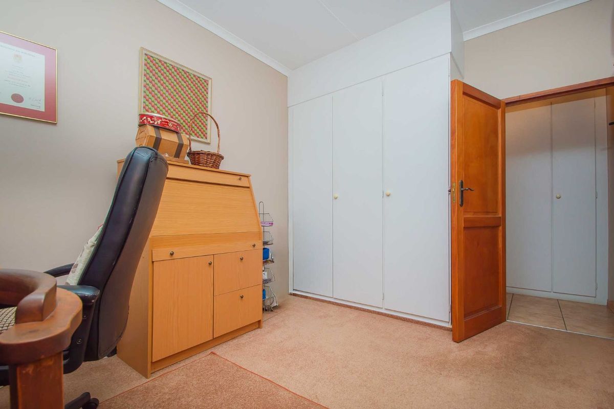 A bedroom featuring built-in cupboards with white doors and a traditional wooden door leading to an adjacent space.