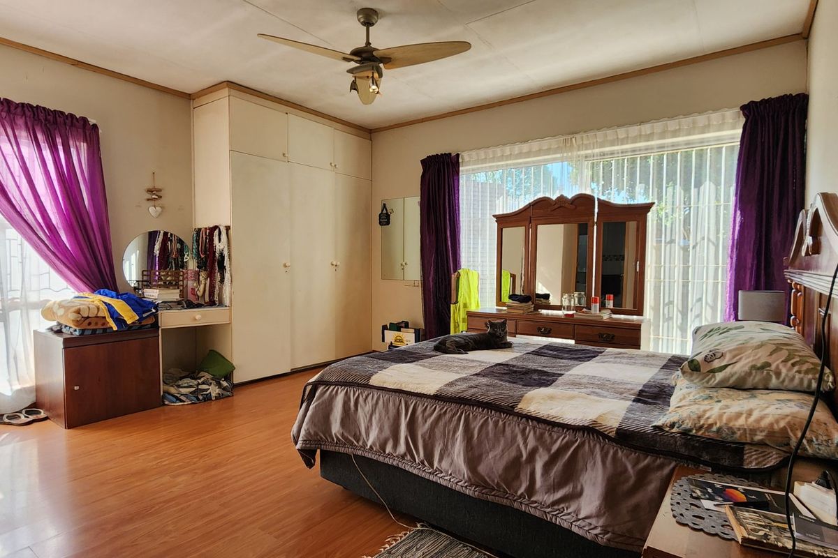 Spacious bedroom featuring built-in wardrobes, laminate flooring, and a ceiling fan, offering a functional layout with ample natural light.