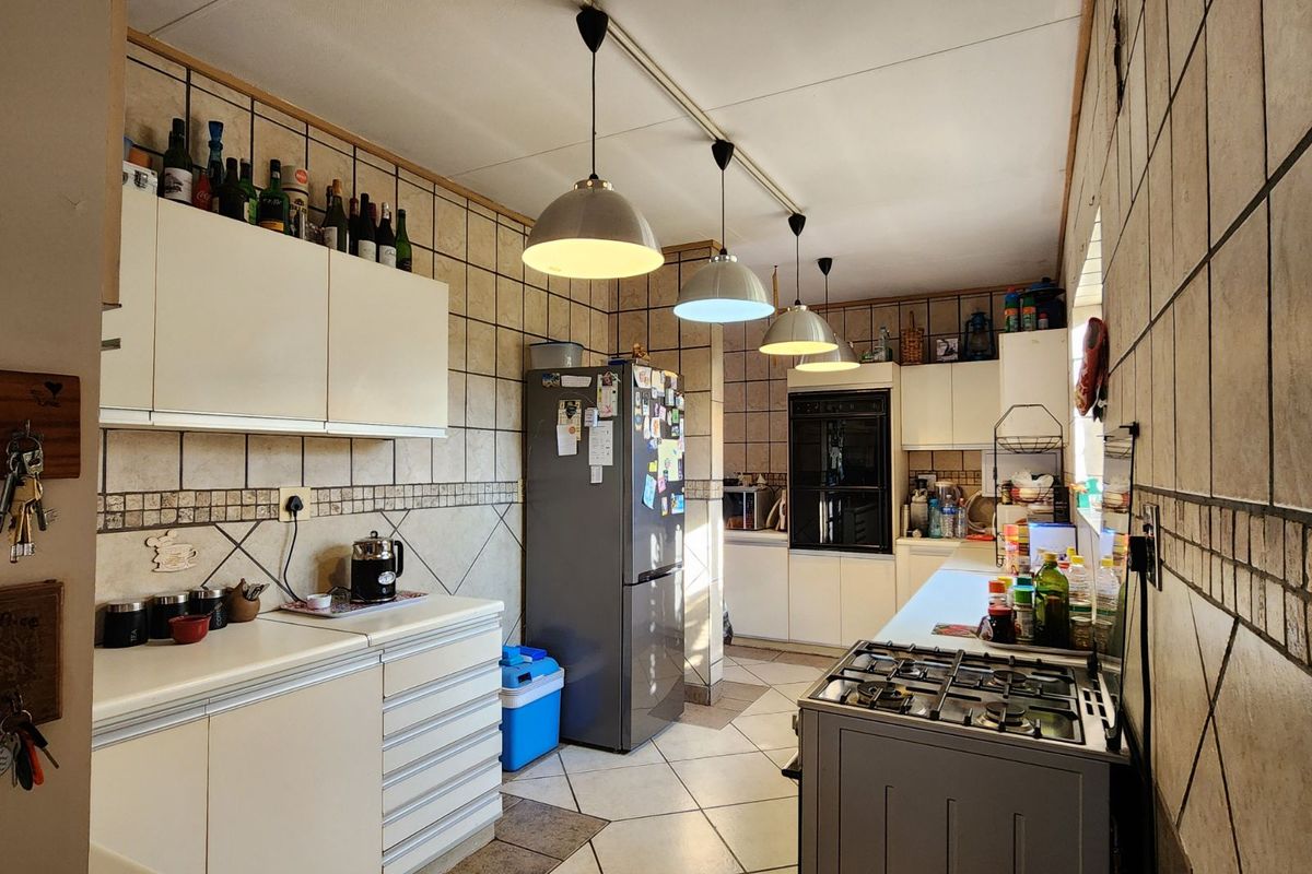 Functional kitchen featuring built-in cabinetry, integrated oven, gas hob, and tiled finishes throughout.