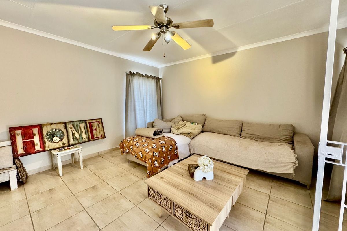 A living room featuring neutral tiled flooring and a ceiling fan, providing a functional and comfortable space for relaxation.