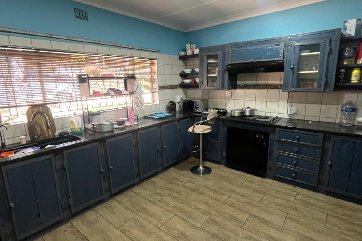 A functional kitchen featuring dark blue cabinetry, dark countertops, a built-in oven with extractor fan, and tiled flooring.