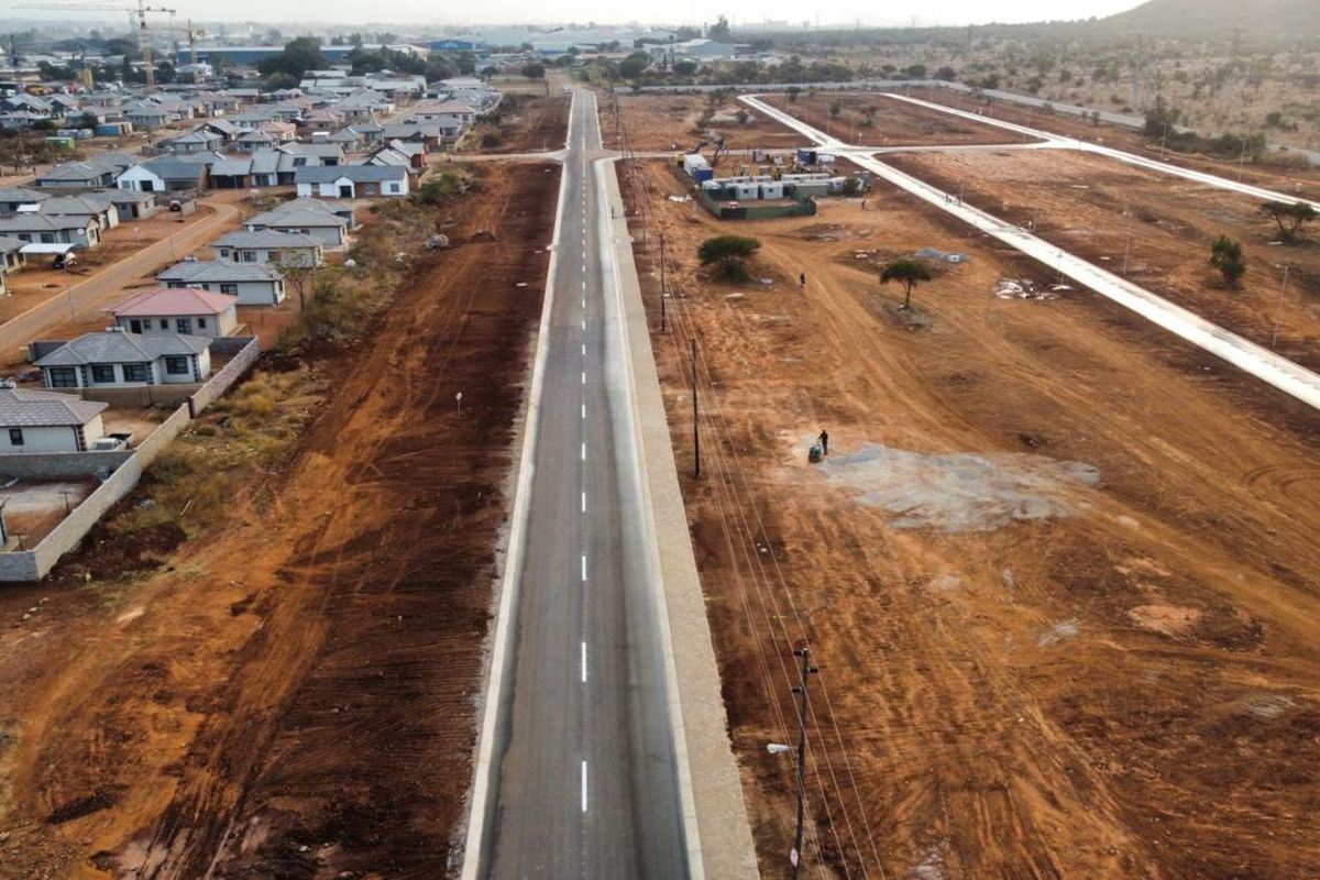 Aerial view of a developing residential estate featuring newly paved roads, infrastructure, and surrounding residential housing units.