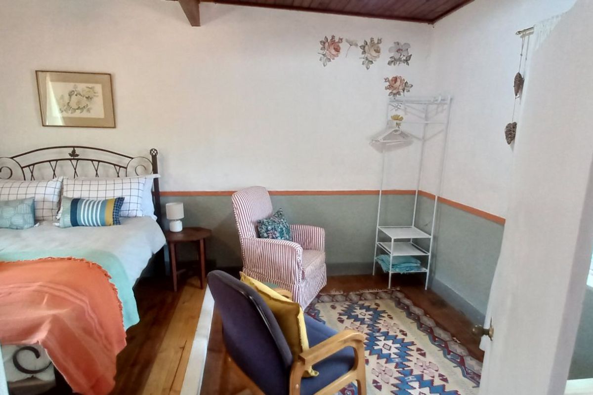 A cozy bedroom featuring warm timber flooring, a timber-paneled ceiling, and a two-tone wall finish with decorative floral accents.