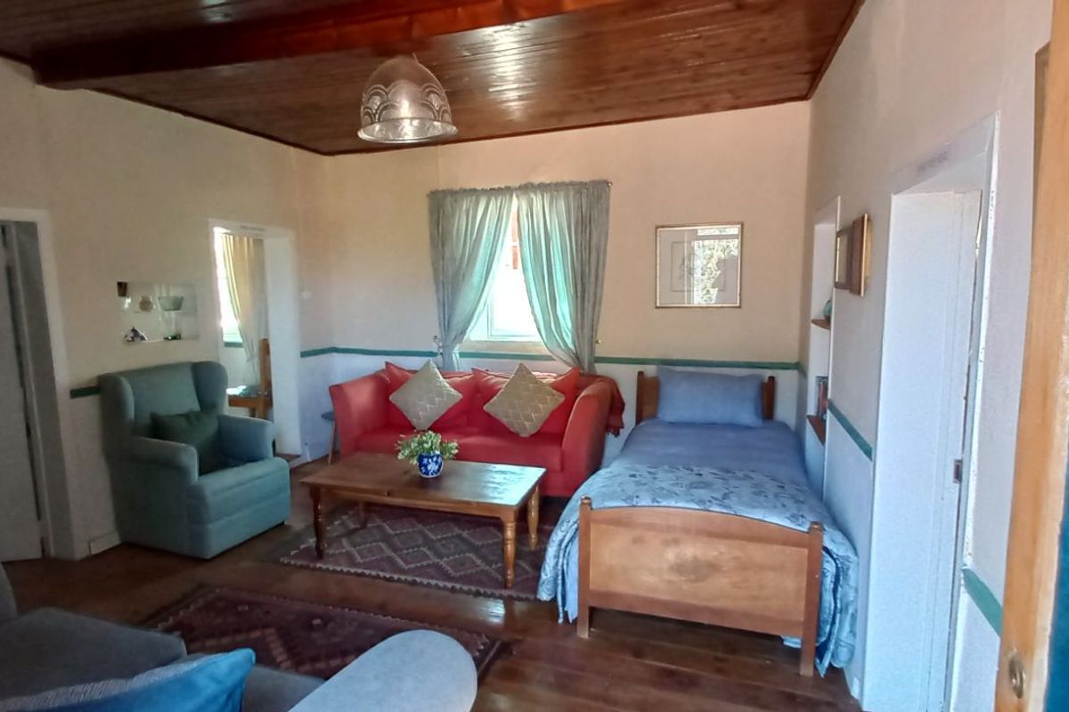 A multi-purpose living and sleeping area featuring timber ceilings, wooden flooring, and a built-in wall niche.