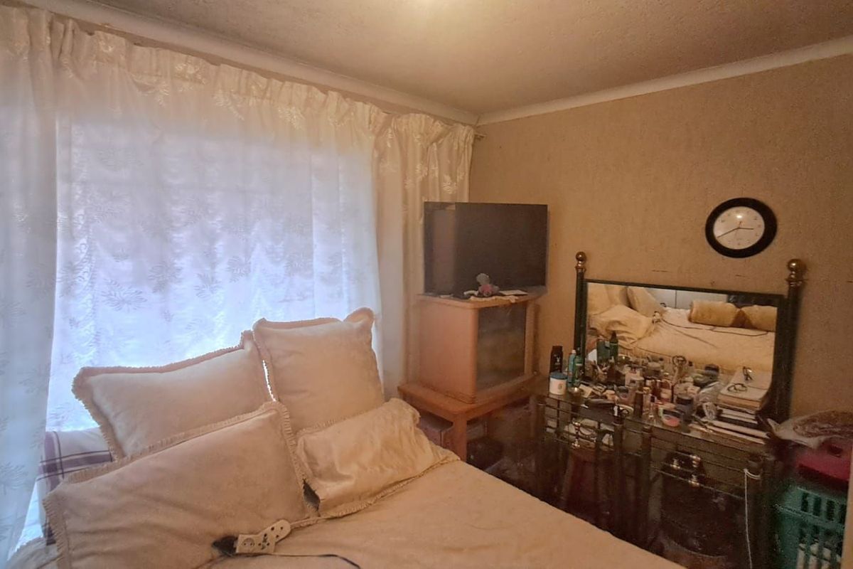 A bedroom featuring a large window with curtains, providing natural light to the space.