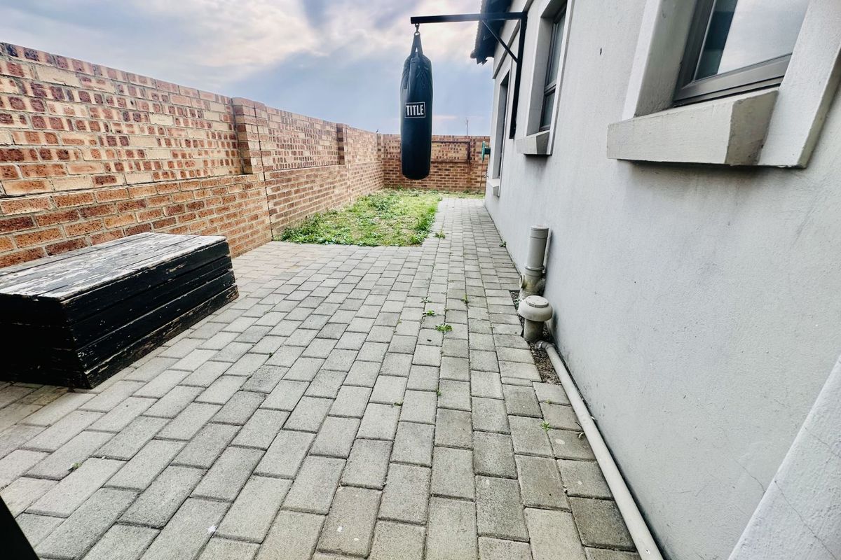 A paved rear courtyard area featuring a brick boundary wall and exterior access to the townhouse.