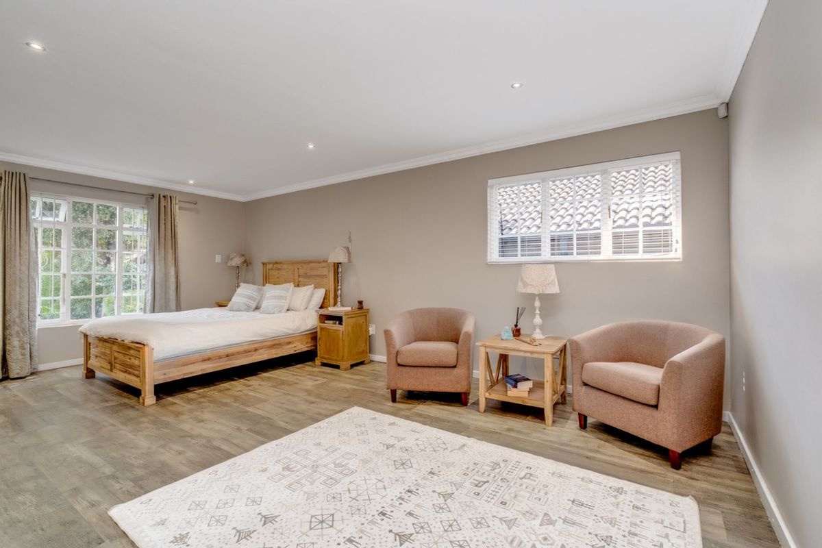 Spacious bedroom featuring wood-look flooring, recessed downlighting, and large windows that provide ample natural light.