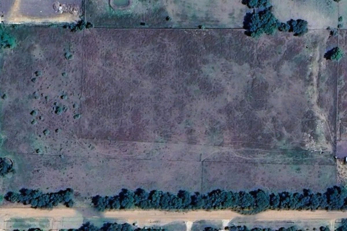An aerial view of a large, undeveloped residential land parcel featuring natural vegetation and perimeter fencing.
