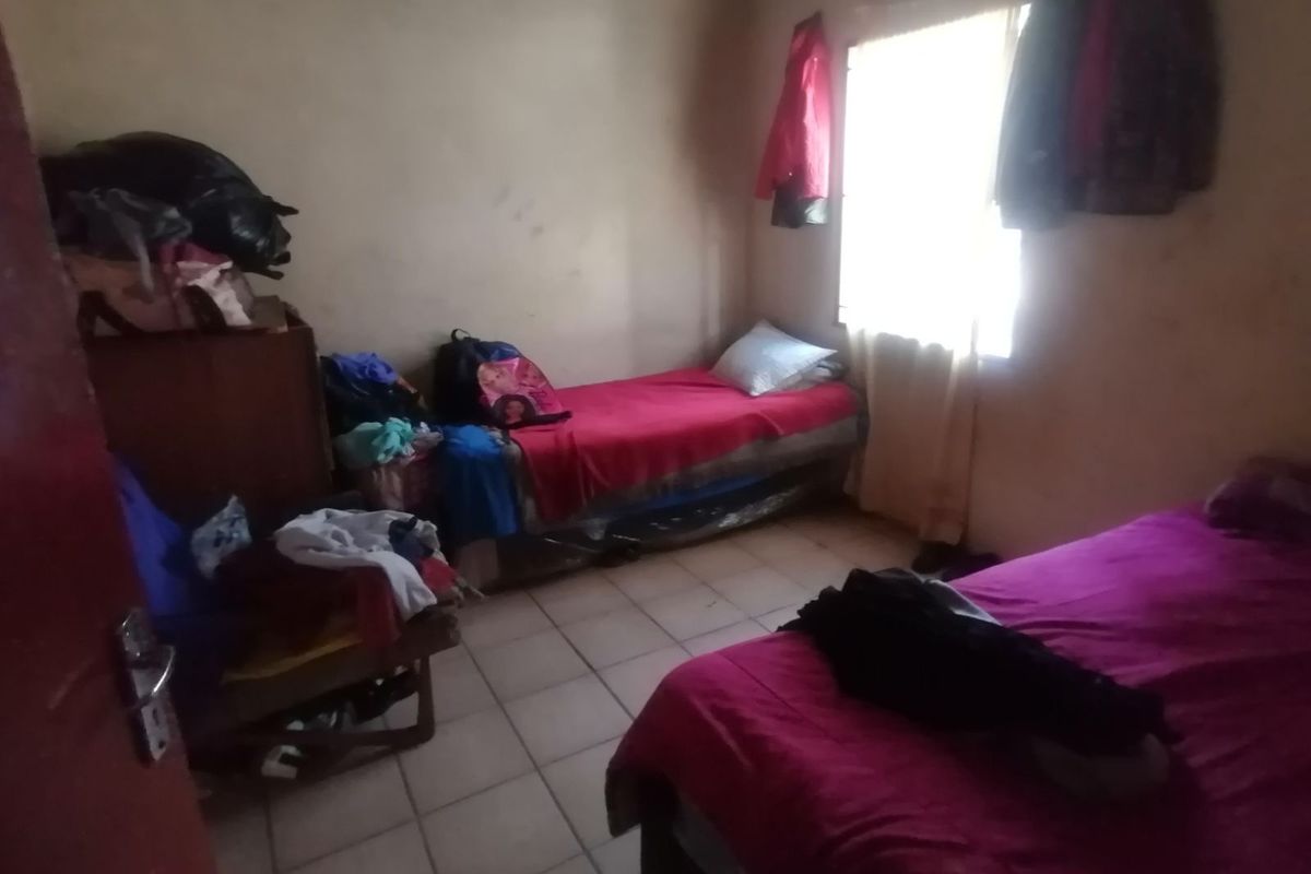 A bedroom featuring tiled flooring and a window, requiring cosmetic updates and maintenance to improve the overall condition of the space.