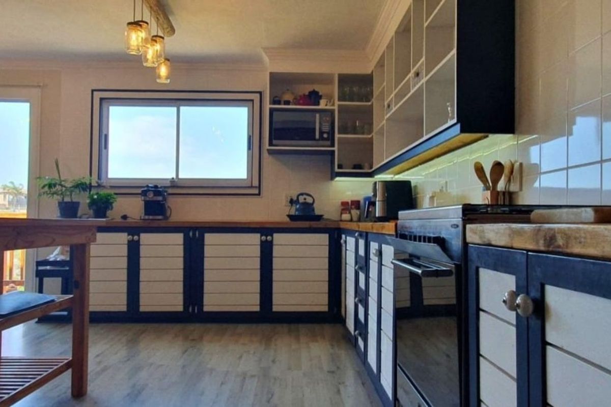 A well-lit kitchen featuring custom cabinetry, wooden countertops, a built-in oven, and a tiled backsplash with modern pendant lighting.