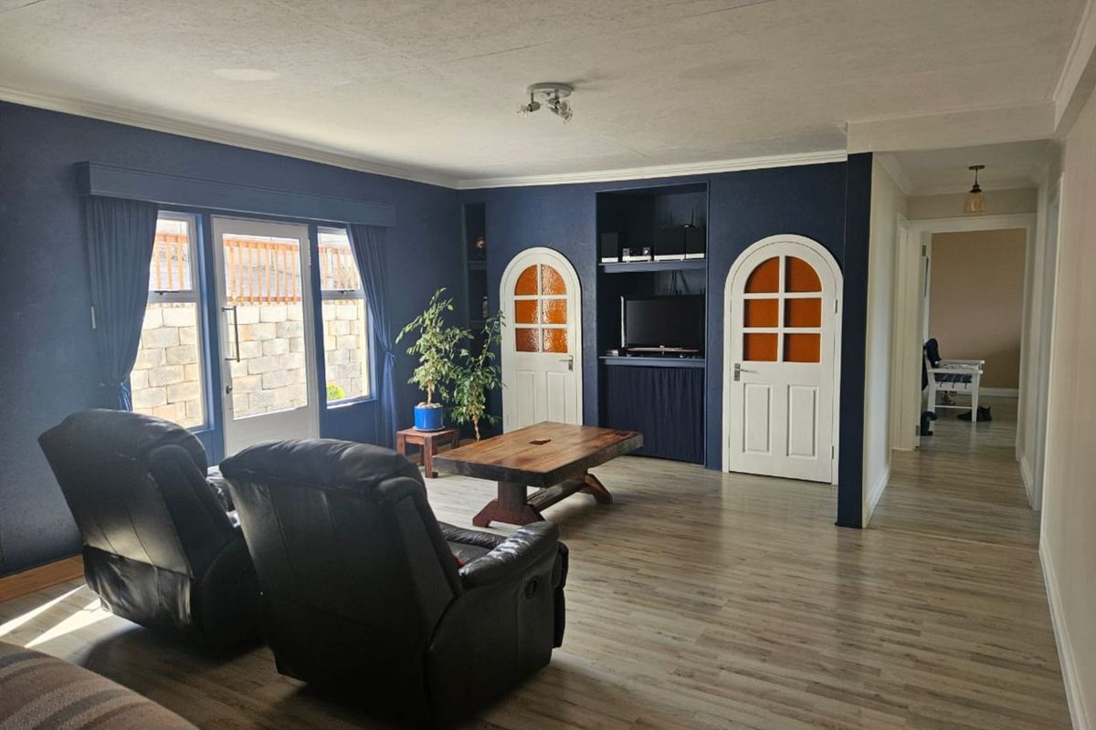 Spacious living room featuring dark blue accent walls, arched interior doors, light wood-look flooring, and direct access to the rear patio area.