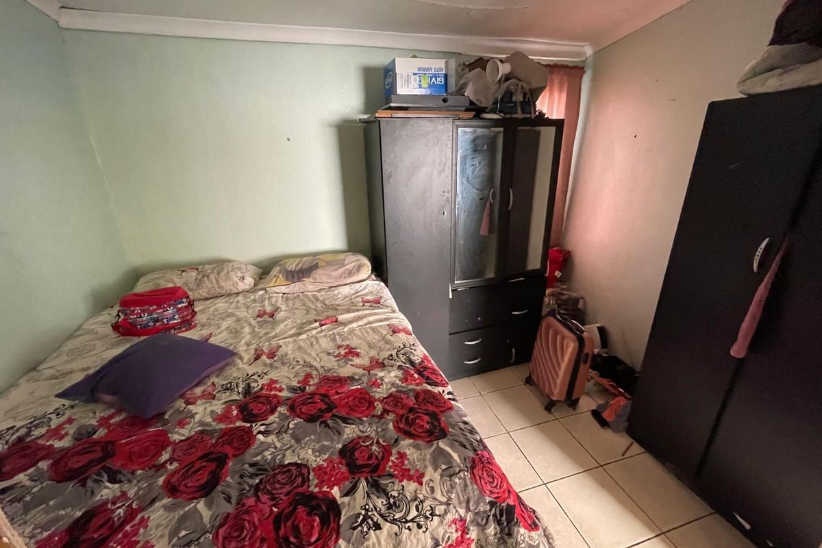A bedroom featuring tiled flooring and standard wall finishes, providing a functional sleeping space.