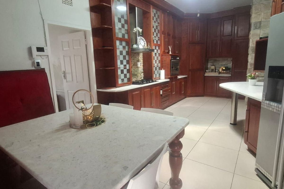 Spacious kitchen featuring dark wood cabinetry, stone countertops, a built-in oven, and a gas hob, with an integrated dining area.