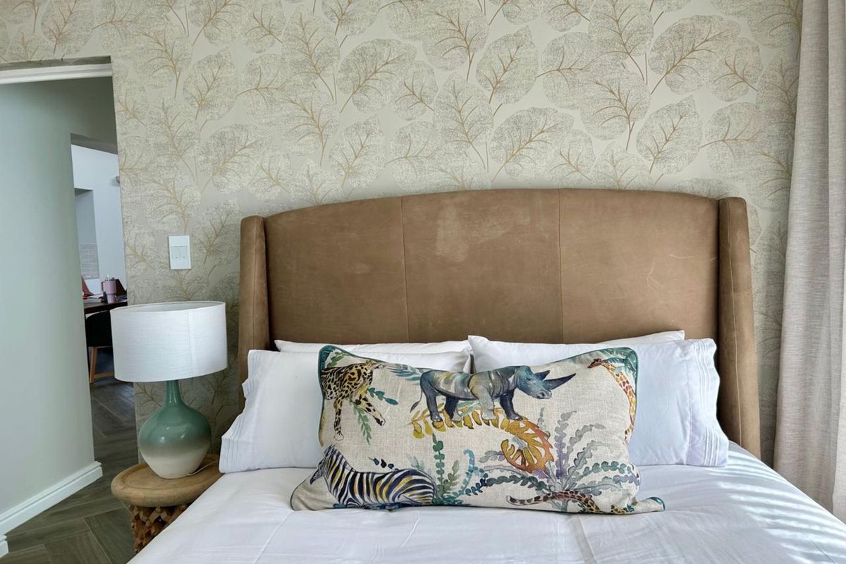A well-maintained bedroom featuring patterned wallpaper and a neutral color palette, providing a comfortable and inviting living space.
