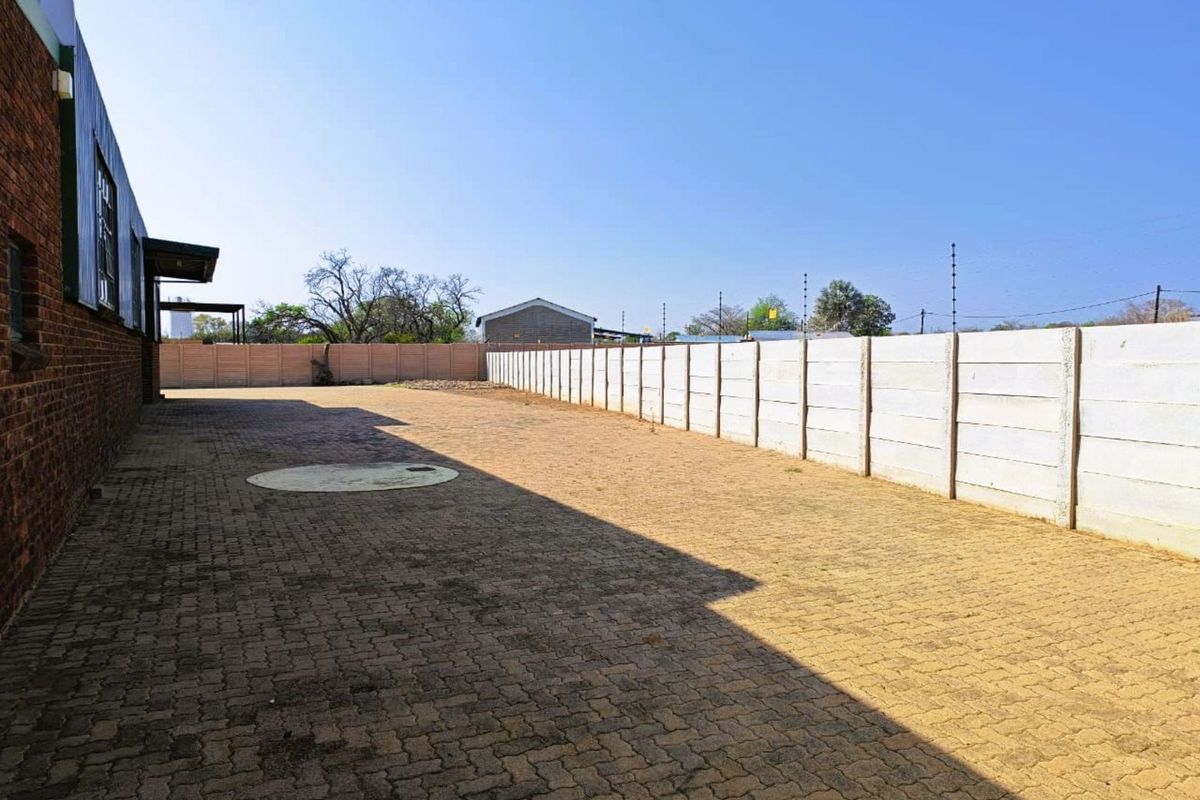 Spacious paved exterior yard area featuring perimeter precast concrete walling and industrial building facade.