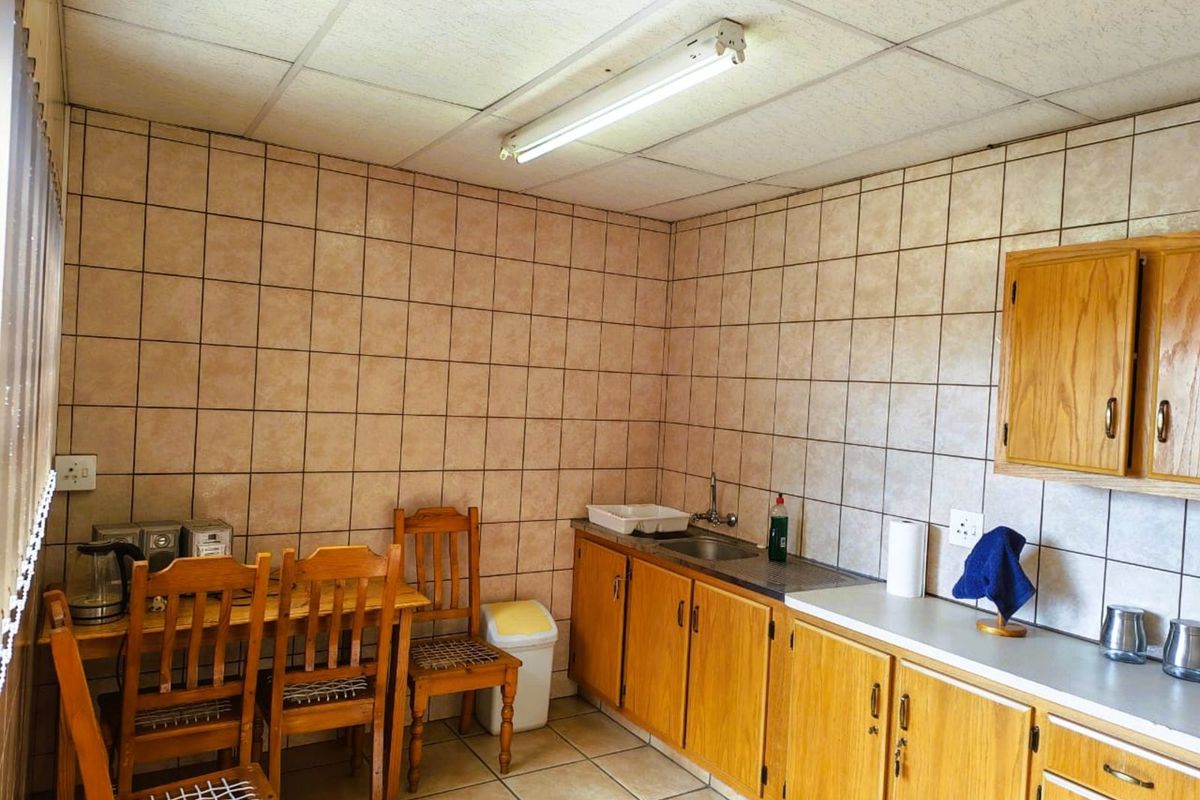 A functional kitchen area featuring wooden cabinetry, tiled walls, and a drop ceiling with fluorescent lighting.