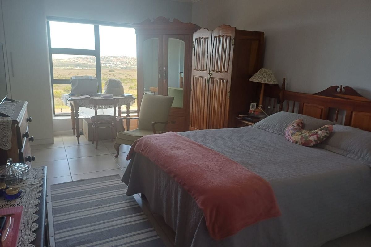 A spacious bedroom featuring large windows with scenic views, tiled flooring, and neutral wall finishes.