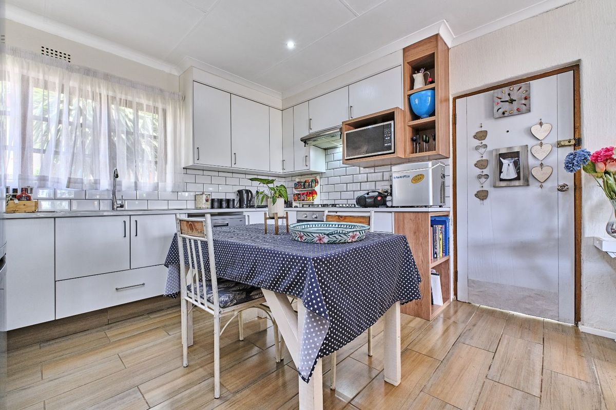 A functional kitchen featuring white cabinetry, subway tile backsplash, wood-look tile flooring, and integrated shelving, providing a practical space for cooking and dining.