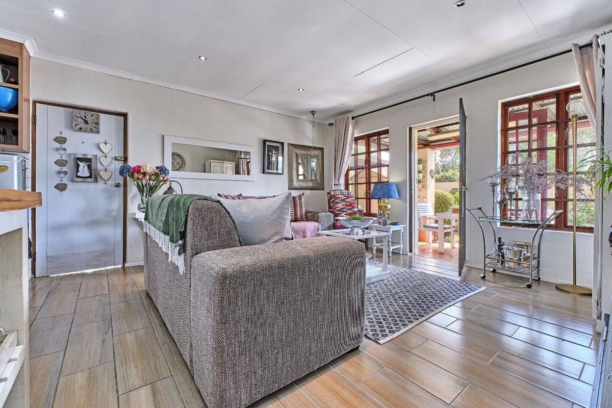Bright living room featuring wood-look tile flooring, recessed ceiling lighting, and direct access to an outdoor patio area through a glass-paned door.