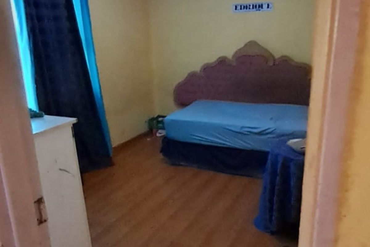 A bedroom featuring laminate flooring and visible ceiling water damage, requiring cosmetic attention and repairs to the ceiling and wall finishes.