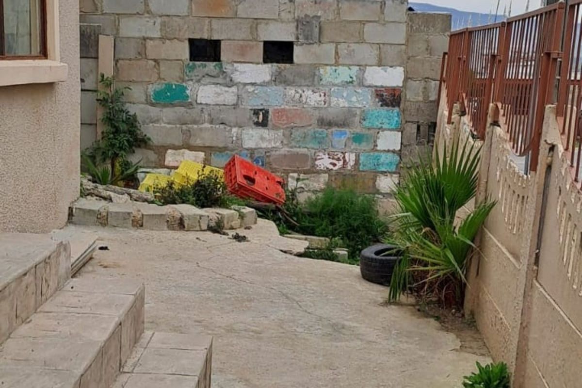 A side exterior area featuring concrete steps, a concrete paved pathway, and a boundary wall constructed from unfinished concrete blocks.