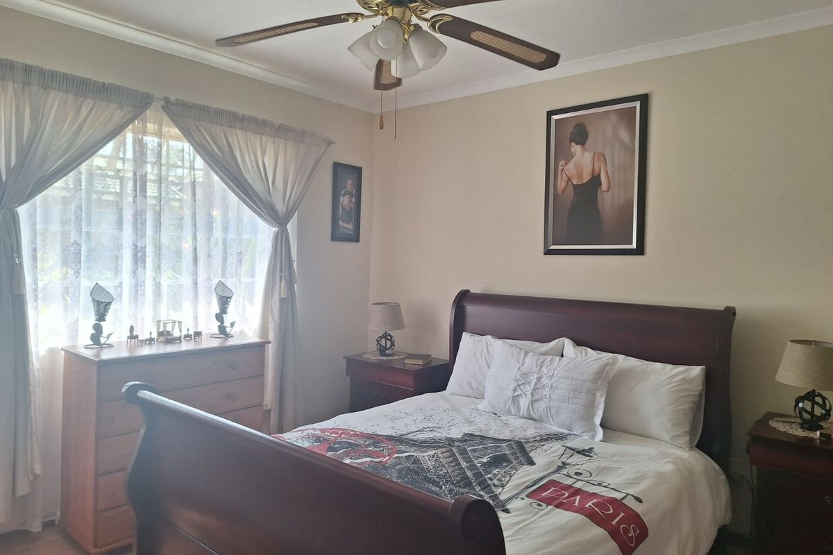 A well-maintained bedroom featuring a ceiling fan and neutral wall finishes, providing a comfortable and functional living space.