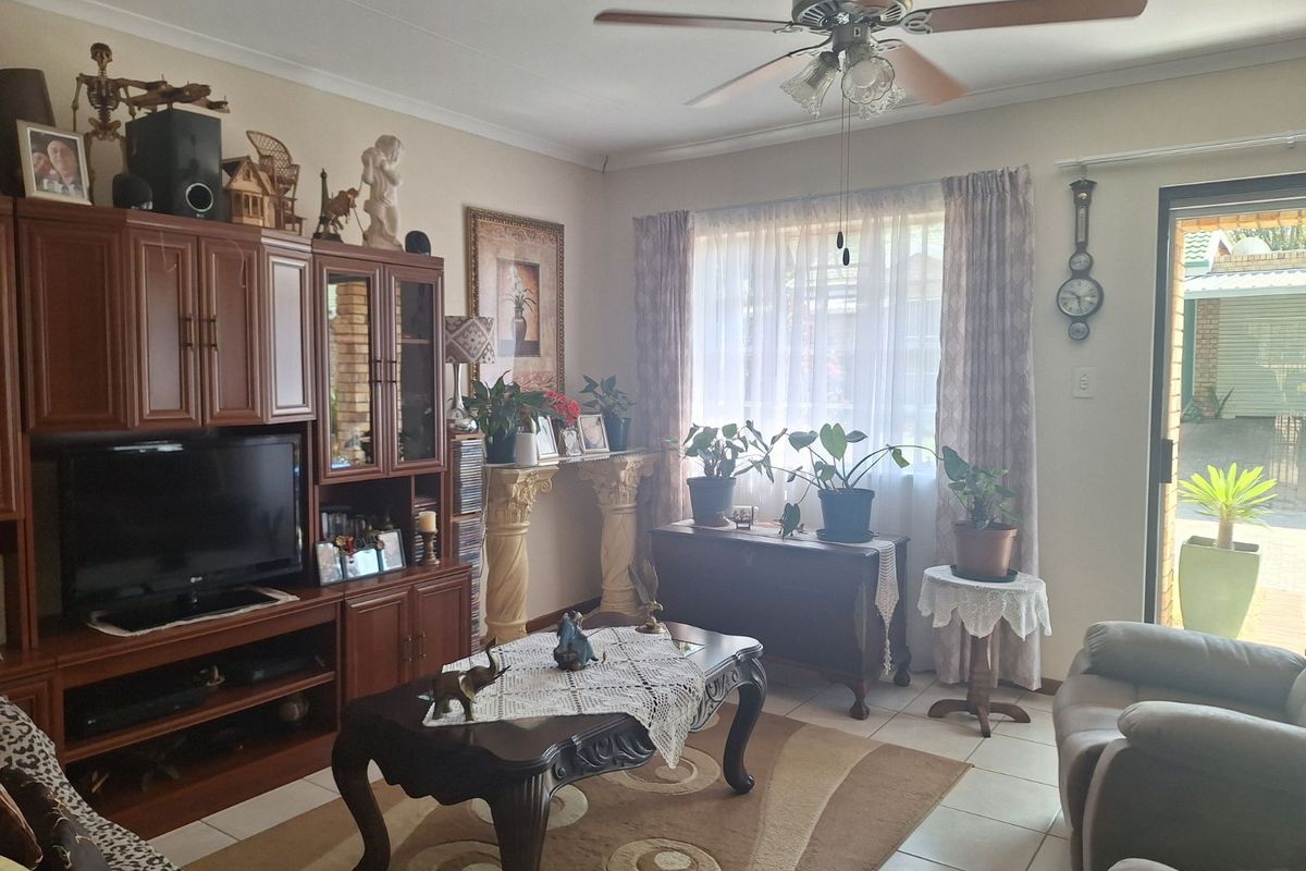 A comfortable living room featuring tiled flooring, a ceiling fan, and a sliding glass door providing access to the outdoor area.