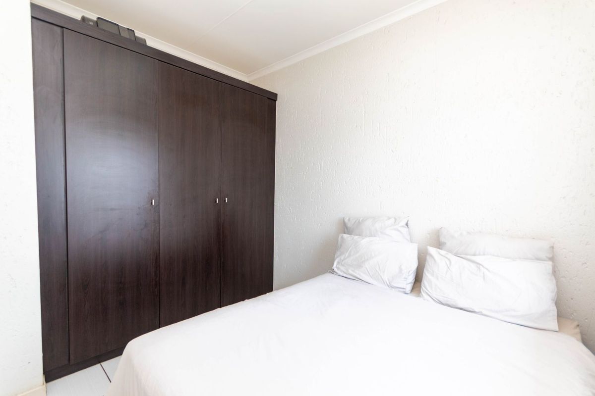 A bedroom featuring built-in dark wood cabinetry and textured wall finishes.