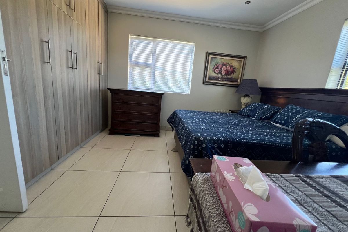A spacious bedroom featuring large built-in wooden wardrobes, tiled flooring, and recessed ceiling lighting.