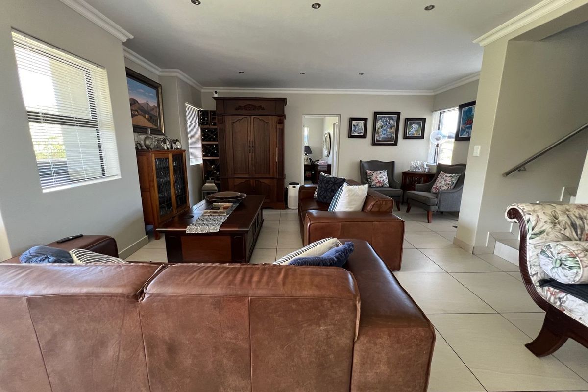 Spacious living room featuring neutral tiled flooring, recessed downlighting, and crown molding, providing a comfortable and well-maintained area for relaxation.