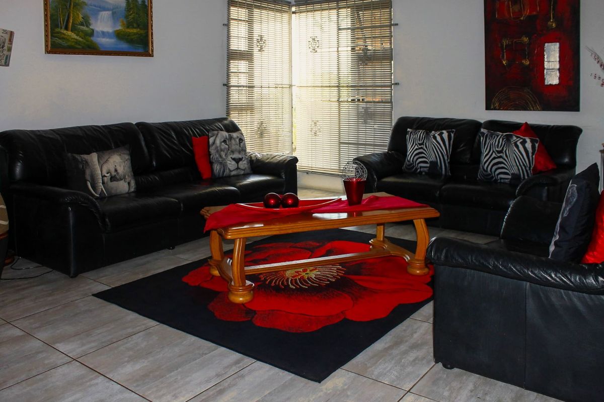 A living room featuring tiled flooring and corner windows fitted with horizontal blinds.