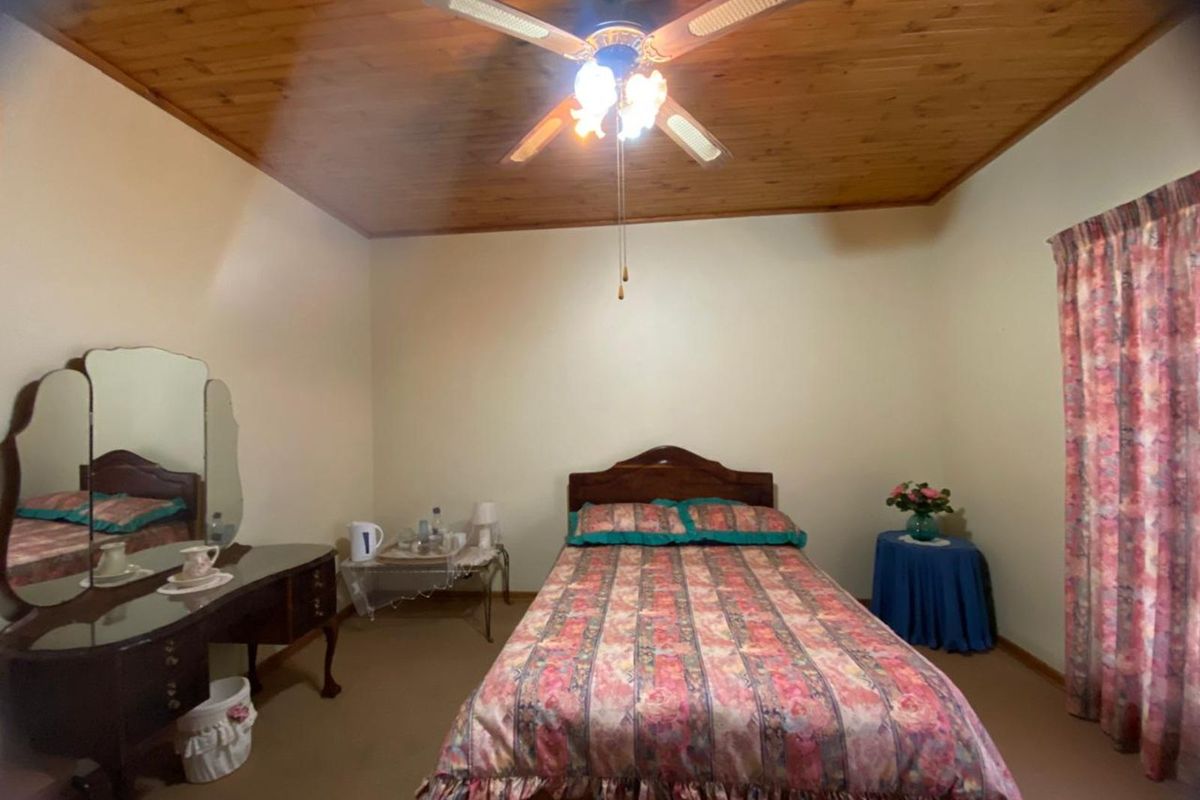 A bedroom featuring a timber-paneled ceiling and a central ceiling fan, providing a traditional aesthetic.