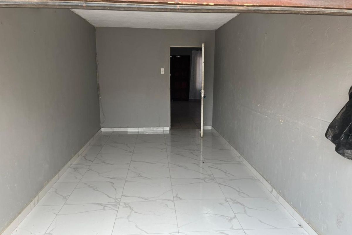 An empty, neutral-toned room featuring modern white marble-look floor tiles and a single doorway leading to an adjacent space.