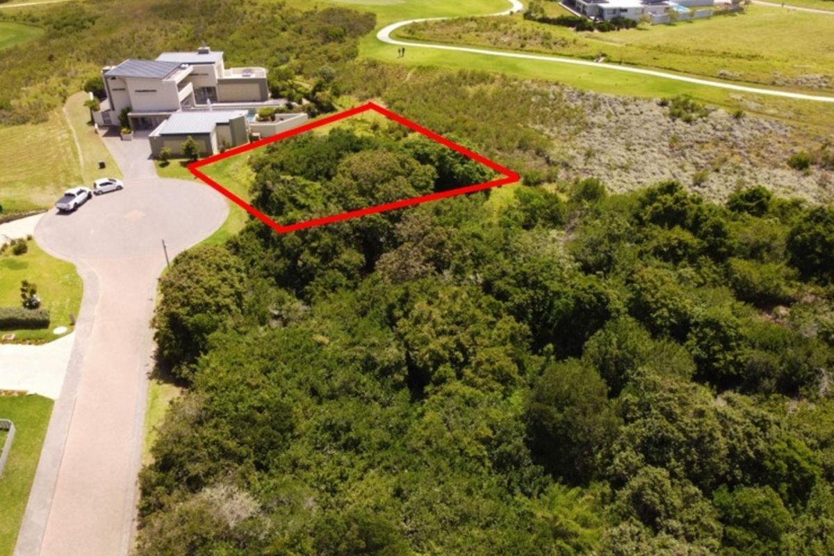 Aerial view of a vacant residential plot in a golf estate, featuring dense natural vegetation and proximity to existing residential infrastructure.