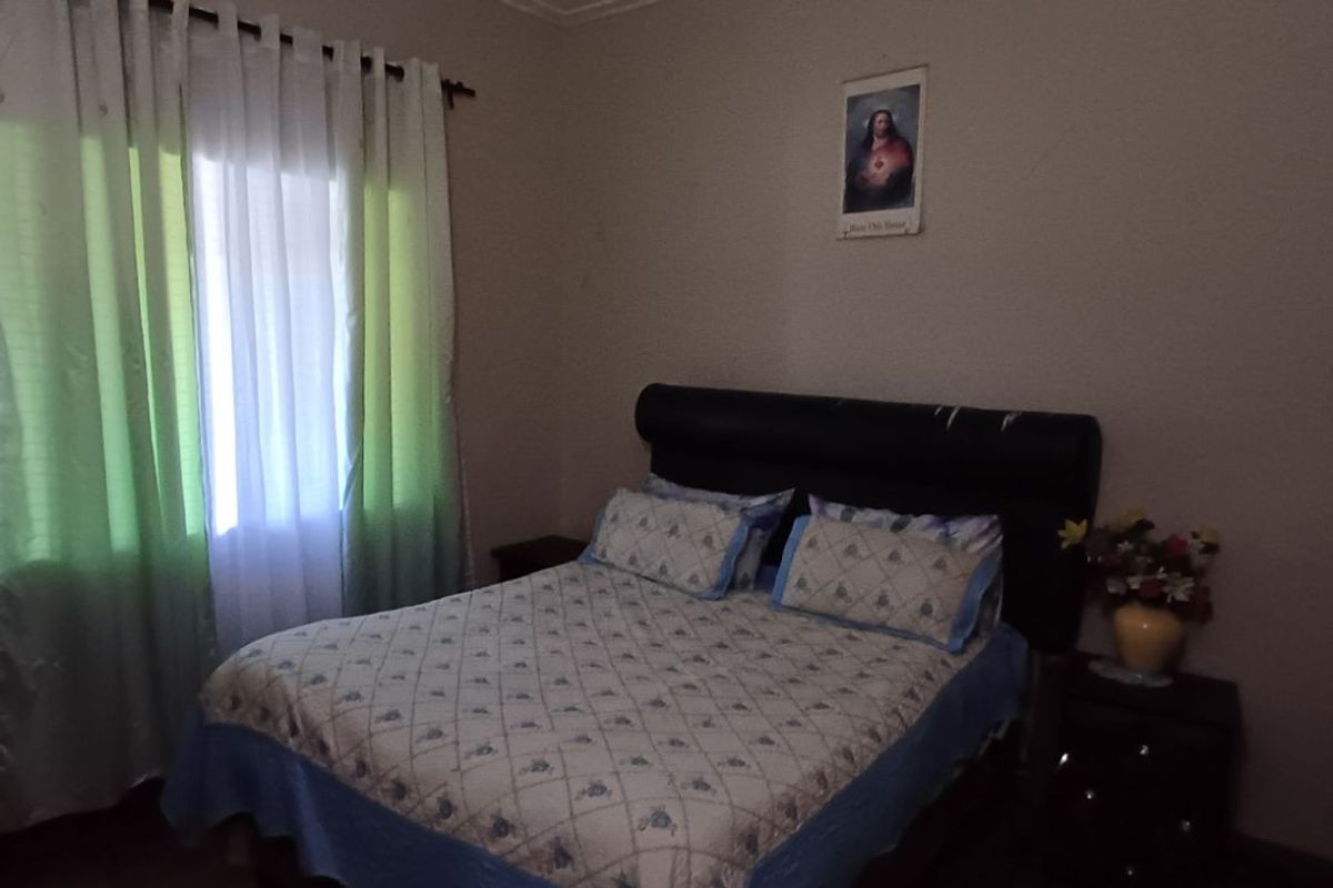 A functional bedroom featuring a built-in wardrobe and natural light from a window with curtain fixtures.