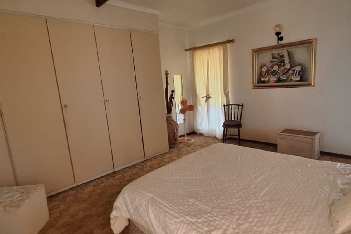 A bedroom featuring built-in cupboards and carpeted flooring, with access to an adjoining outdoor area.