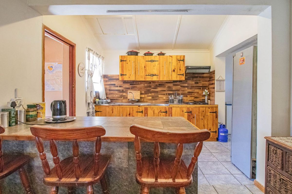 A functional kitchen featuring wooden cabinetry, tiled backsplash, and a breakfast bar island, providing a practical layout for daily meal preparation.
