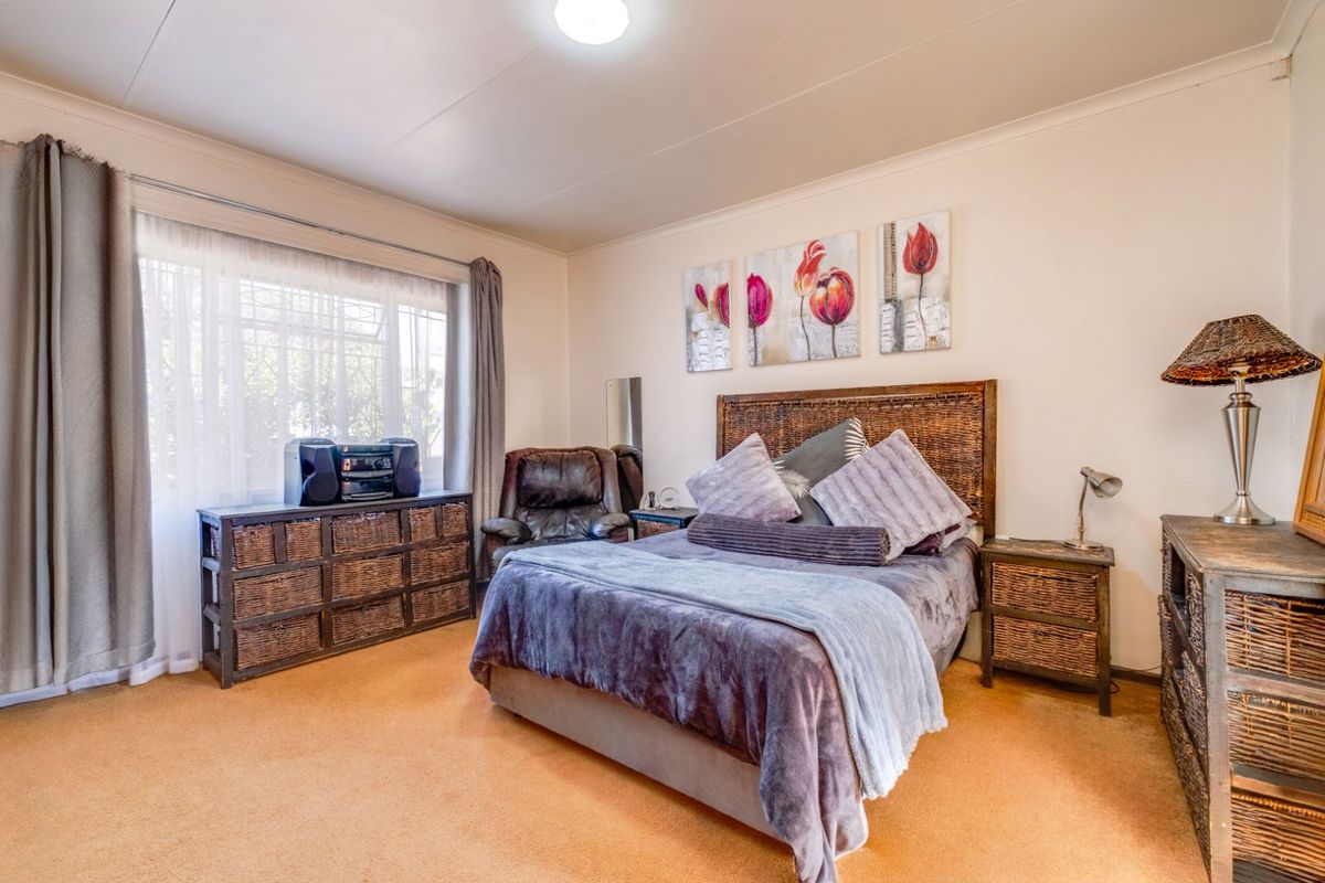 A standard bedroom featuring carpeted flooring, a large window with curtains, and a central ceiling light fixture.