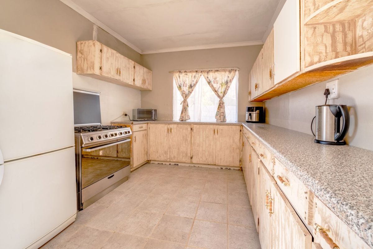 A functional kitchen featuring laminate countertops, built-in cabinetry, and a freestanding gas stove, offering a practical layout with natural light.