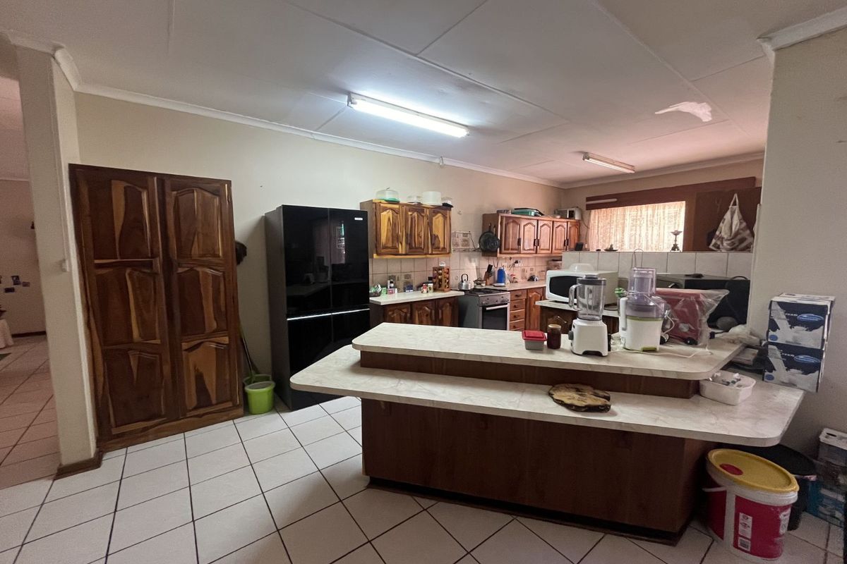 A functional kitchen featuring wooden cabinetry, a breakfast bar, tiled flooring, and built-in storage, offering a practical layout for daily meal preparation.
