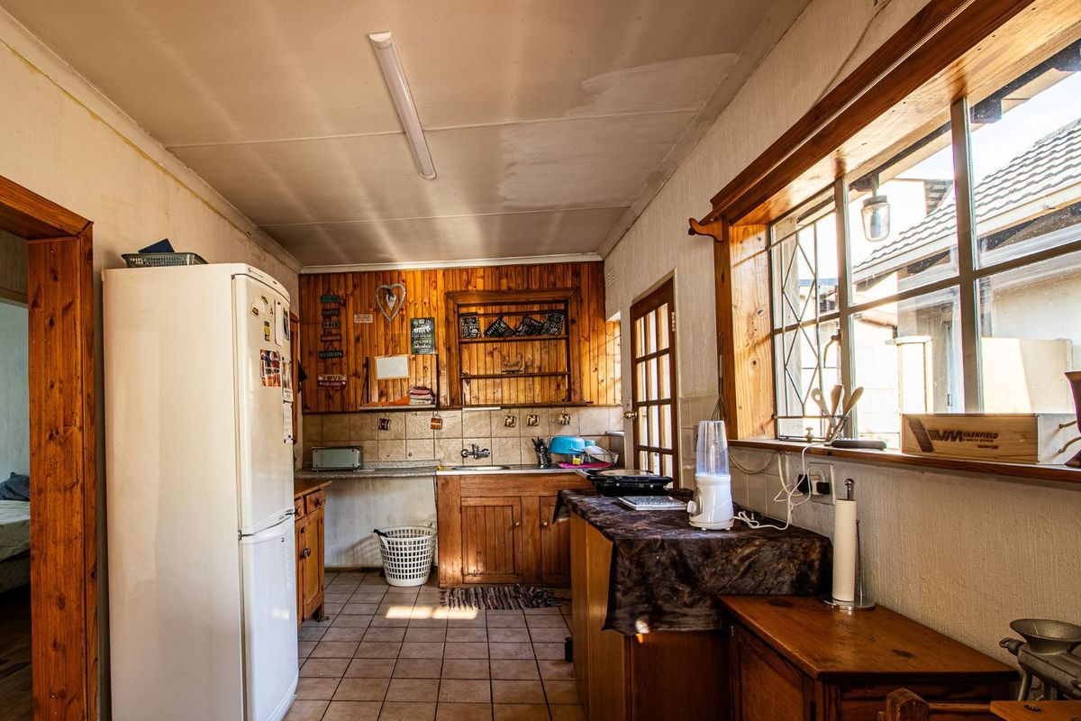 A dated kitchen featuring timber cabinetry, tiled splashbacks, and tiled flooring, offering potential for a modern renovation.