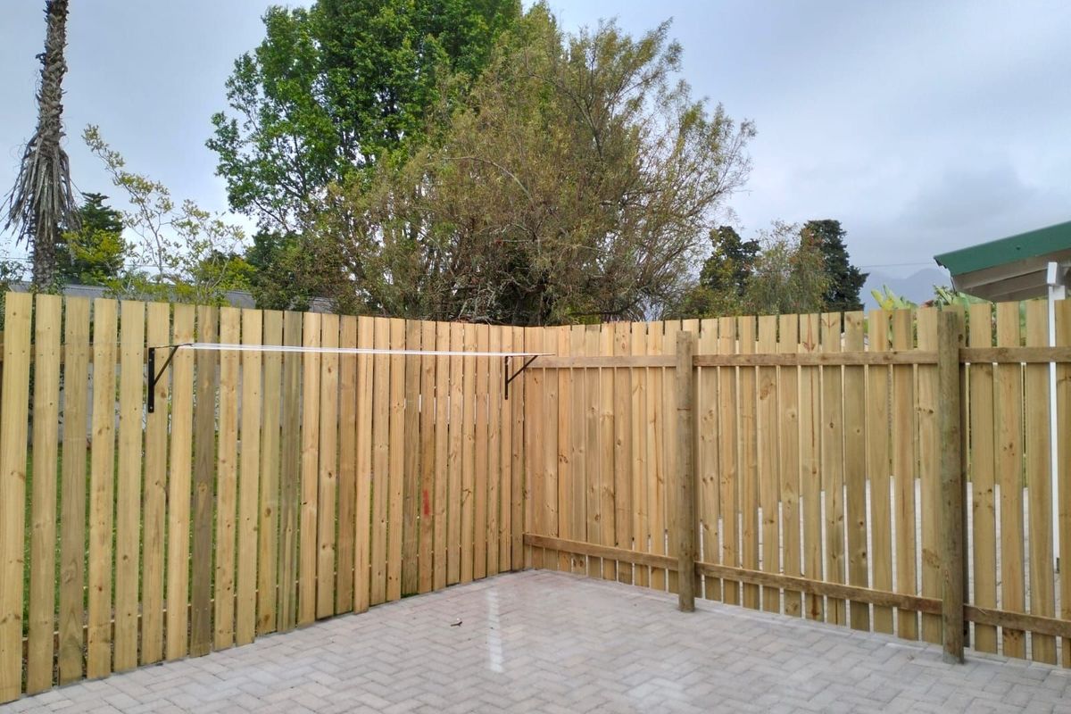 A private rear courtyard area featuring paved flooring and a newly installed timber perimeter fence with a wall-mounted clothesline.