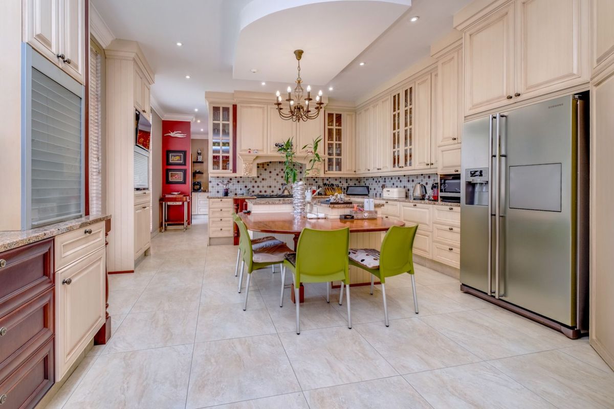 Spacious kitchen featuring cream cabinetry, mosaic tile backsplash, recessed lighting, and a central island with integrated seating area.