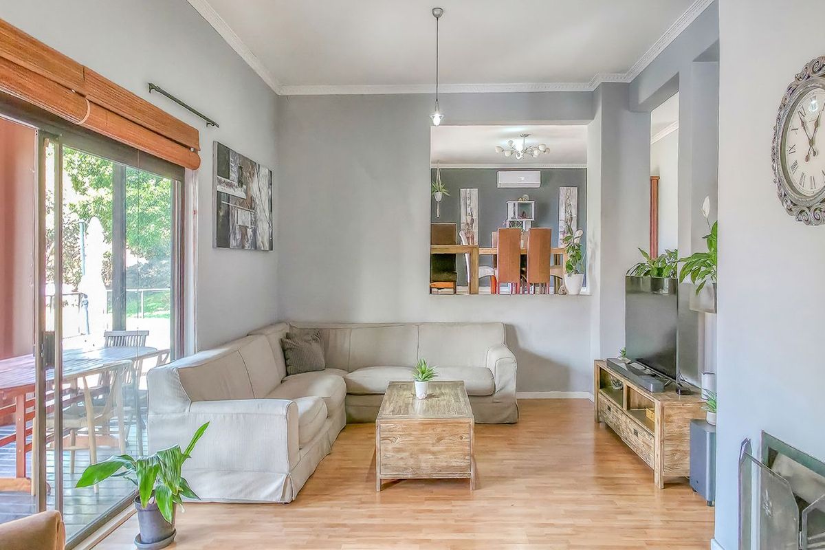 A bright living room featuring light wood flooring, crown molding, and large sliding glass doors that provide seamless access to the outdoor patio area.