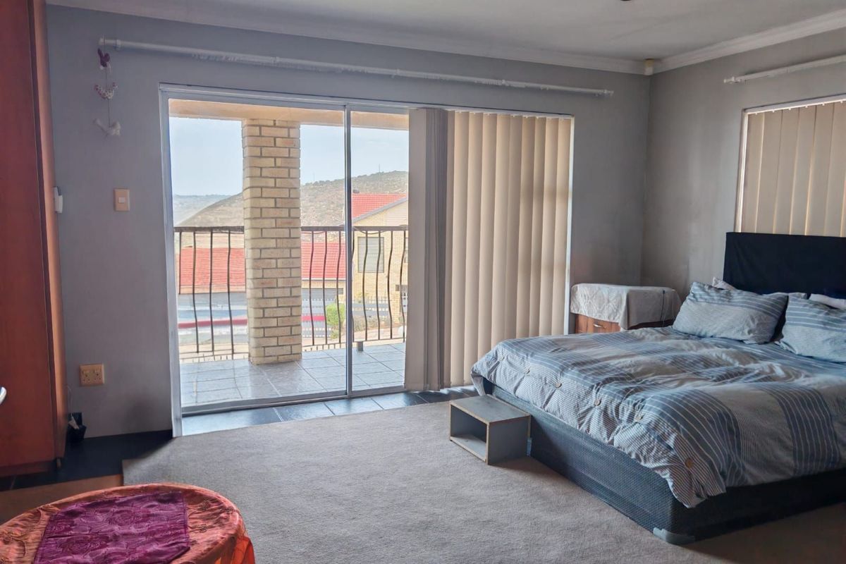 Spacious bedroom featuring large sliding glass doors that open onto a private balcony with scenic views.