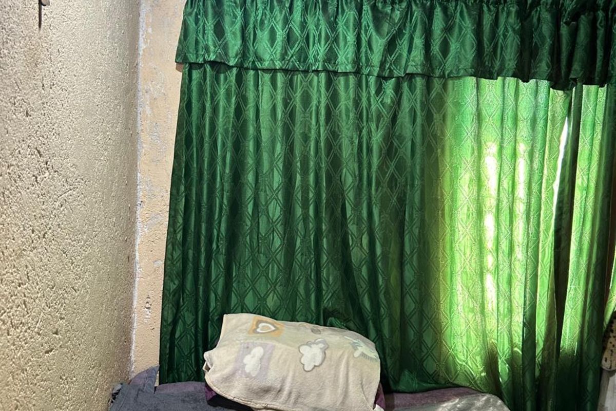 A bedroom space featuring textured walls and a corrugated metal ceiling, requiring significant cosmetic updates and finishing work.