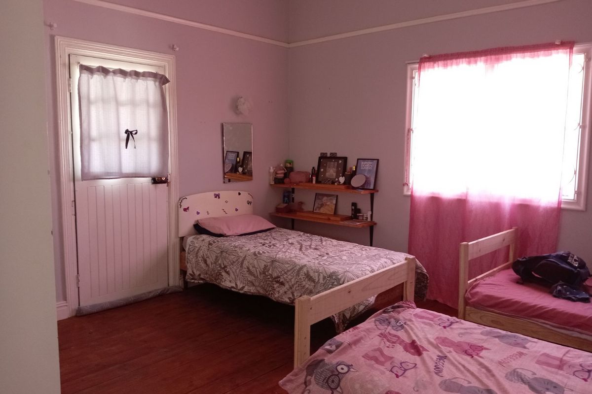 A bedroom featuring timber flooring, high ceilings, and a door providing direct outdoor access.